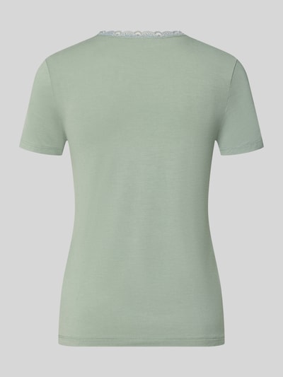 Frauenmodel trägt Slim Fit T-Shirt aus Viskose-Mix mit Spitzenbesatz von Christian Berg Woman in zartem Mintgrün, Ganzkörperansicht Rückansicht. Elastischer Stoff, schlichte Struktur, dezenter Spitzenbesatz am Rundhalsausschnitt.