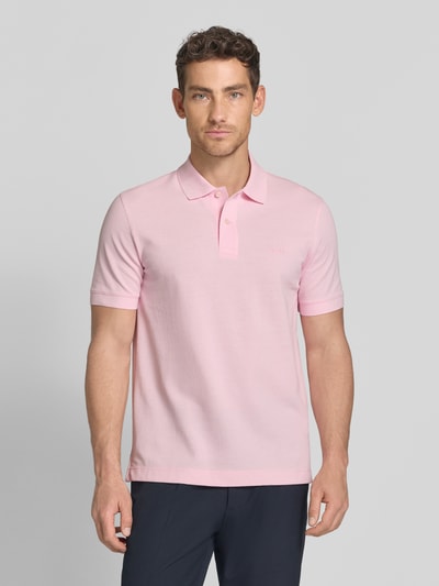Männermodel trägt Regular Fit Poloshirt aus reiner Baumwolle Modell 'PALLAS' von BOSS, Optik: Unifarben, Label-Stitching-Applikation, Polokragen, V-Ausschnitt, kurze Knopfleiste, Kurzarm, Ärmelabschluss: Gerippt, Rumpfabschluss mit Seitenschlitzen, Materialverarbeitung: Piqué, Farbe: Hellrosa, Struktur: Feintextur, Ganzkörperansicht von vorne.