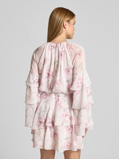 Modelka nosi sukienkę mini z szyfonu od Ted Baker, model 'MAHLIIA', kwiatowy wzór, szerokie rękawy z falbanami, dół obszyty falbaną, okrągły dekolt, tylny zamek błyskawiczny i wycięcie w kształcie łezki z guzikiem, długość tyłu w rozmiarze 36: 39 cm, szerokość w rozmiarze 36: 44 cm, długość rękawów w rozmiarze 36: 46 cm, widok całej sylwetki od tyłu.