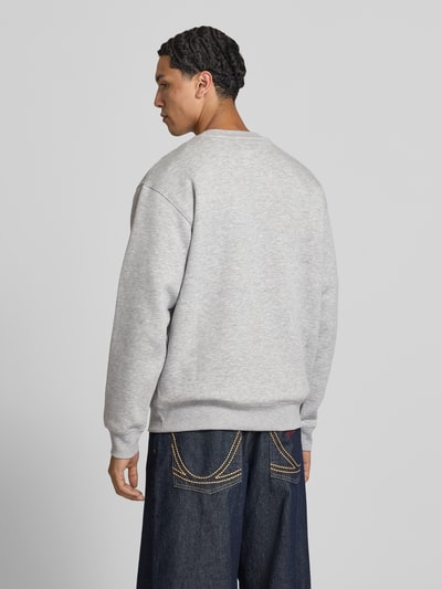 Männermodel trägt Sweatshirt mit Rundhalsausschnitt und Label-Stitching von New Balance, grauer Baumwoll-Mix, Relaxed-Fit, Ganzkörperansicht Rückansicht.