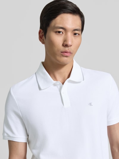Männermodel trägt Poloshirt mit Logo Stitching aus reiner Baumwolle von CK Calvin Klein, Optik: Unifarben, Passform: Regular-Fit, Ausschnitt: Polokragen, Ärmelform: Kurzarm, Material: Reine Baumwolle, Nahaufnahme Oberkörper.