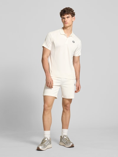 Männermodel trägt Regular Fit Poloshirt mit Logo-Stitching Modell 'EGEO' von SERGIO TACCHINI in Creme, Kurzarm, Polokragen, Ganzkörperansicht von vorne.