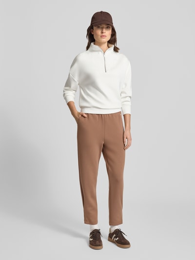 Modelka nosi Oversized Sweatshirt mit Troyer-Kragen von Fynch-Hatton, mieszanka wiskozy z dodatkiem streczu, krój oversized, kołnierz zapinany, krótki zamek błyskawiczny, prążkowane wykończenia, kolor biały, widoczne gładkie tekstury i proste formy; widok całej sylwetki z przodu.