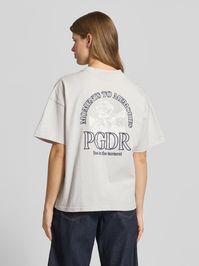 Modelka nosi Oversized T-Shirt mit Label-Stitching Modell 'MARIALVA' od Pegador, bawełna, dekolt okrągły, kolor jasny, widoczne zdobienie na plecach, długość pleców w rozmiarze S: 61 cm, widok całej sylwetki z tyłu