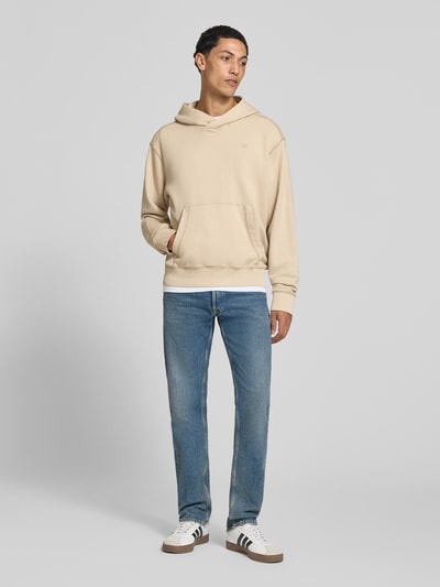 Mannelijk model draagt Slim Fit jeans uit katoenmix Model 'Grover' van Replay, mix van katoen en elastaan, slim fit, knoop- en ritssluiting, 5-pocketmodel, bandwijdte maat 32/32: 42 cm, binnenbeenlengte maat 32/32: 80 cm, volledig lichaam vooraanzicht.