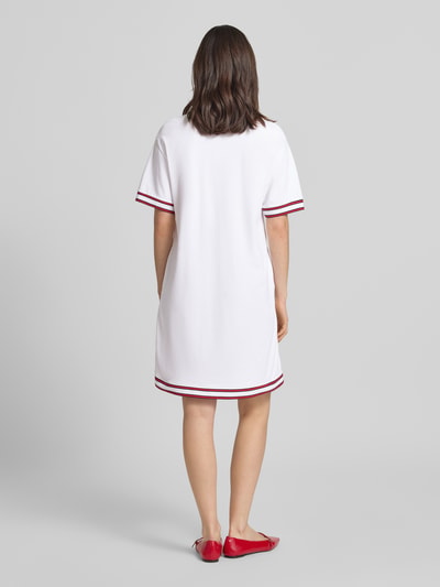Frauenmodel trägt Knielanges Polokleid mit Label-Stitching Modell 'Tasa' von JOOP! aus Baumwoll-Elasthan-Mix, Weiß mit roten Kontraststreifen, Gerader-Schnitt, Knielänge, Ganzkörperansicht Rückansicht.