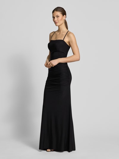 Frauenmodel trägt Abendkleid mit Raffungen und rückseitiger Schnürung von TROYDEN COLLECTION, figurbetonter Schnitt, Maxikleid, Spaghettiträger, schwarzer Stoff, glatte Textur, Ganzkörperansicht von vorne.