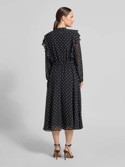 Vrouwenmodel draagt Midikleid im Allover-Look mit Bindegürtel van JOOP!, zwarte stof met witte stippen, model in a-lijn, volants, ronde hals, strikceintuur, ruglengte maat 36: 120 cm, borstwijdte maat 36: 47 cm, mouwlengte maat 36: 63 cm, ganzlichaamsaanzicht achteraan.