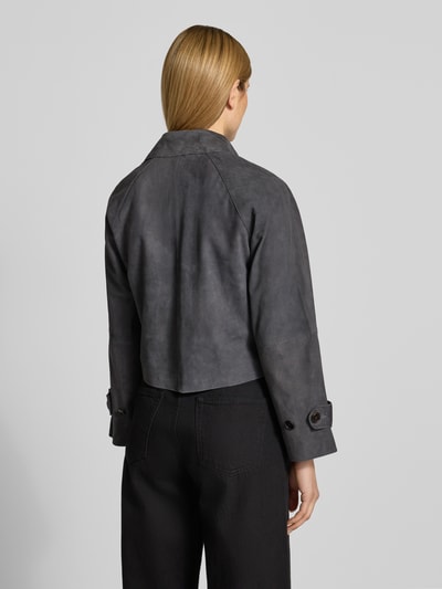 Modelka nosi Regular Fit Trenchcoat aus echtem Ziegenleder od Marc O'Polo, szary kolor, optyka zamszowa, kołnierz z klapami, długie rękawy, kieszenie boczne, materiał: skóra kozia, widok całej sylwetki z tyłu.