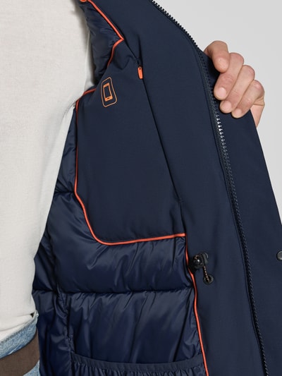 Männermodel trägt donkerblau jack met oranje details, regular fit, hoge kraag, klepzakken, model 'WILSON' van Save The Duck, ruglengte maat M 89 cm, schouderbreedte 46 cm, borstwijdte 51 cm, mouwlengte 68 cm, detailopname bovenlichaam.