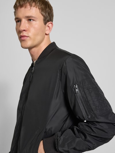 Męski model nosi Regular Fit Bluzon z college'owym kołnierzem Model 'JOSHUA' od Only & Sons, jednolity kolor, zamek błyskawiczny, długi rękaw, prążkowane zakończenia, boczne wpuszczane kieszenie, kieszeń na rękawie na zamek, zdjęcie z przodu, zbliżenie na górę ciała.
