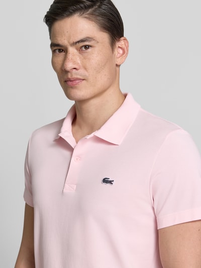 Männermodel trägt Regular Fit Poloshirt aus Baumwoll-Mix von Lacoste, Optik: Unifarben, Logo-Patch, Polokragen, Kurzarm, Nahaufnahme Oberkörper.