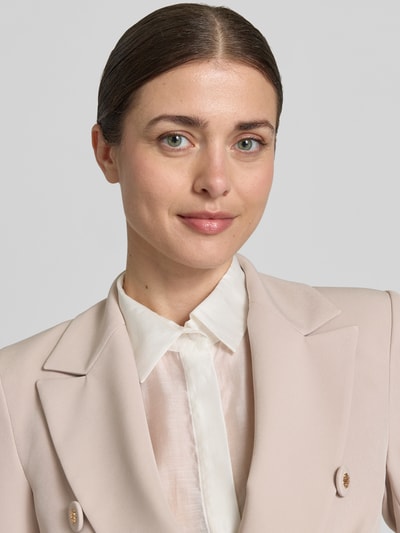 Frauenmodel trägt Blazer mit Pattentaschen Modell 'REWI' von Rinascimento in hellem Beige, glatter Stoff, Nahaufnahme Oberkörper.