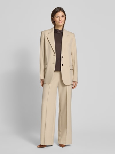 Frauenmodel trägt Wide Fit Stoffhose mit Viskose-Anteil Modell 'Paris' von Mango in Beige, elegante Bügelfalten, Ganzkörperansicht von vorne.