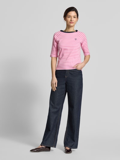 Frauenmodel trägt Shaped Fit T-Shirt aus reiner Baumwolle von Tom Tailor Denim, rosa-weiß gestreift, Rundhals, Kurzarm, Feinripp, Label- und Herz-Stitching, Ganzkörperansicht von vorne.