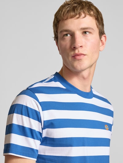 Männermodel trägt Herren T-Shirt von Dickies in Blau-Weiß mit Streifen, Reine Baumwolle, Regular-Fit, Label-Stitching, Rundhalsausschnitt, Nahaufnahme Oberkörper. Modell 'RIVERGROVE', Rückenlänge bei Größe M: 71 cm.