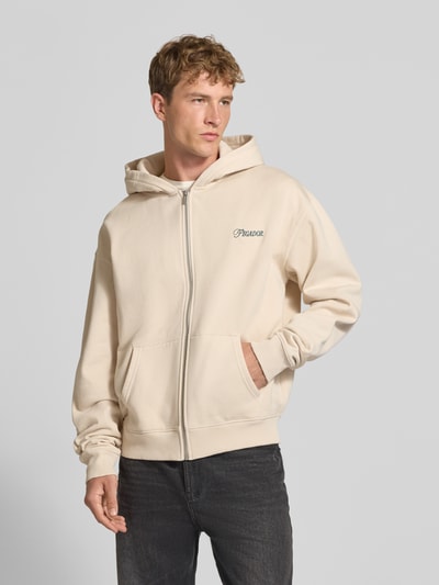 Männermodel trägt Relaxed Fit Sweatjacke aus Baumwoll-Mix Modell 'Carloforte' von PEGADOR in Beige, geteilte Kängurutasche, Logo-Stickerei, Langarm, gerippte Abschlüsse, überschnittene Schultern, Vorderansicht Oberkörper