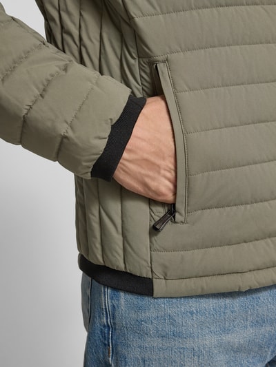 Männermodel trägt Steppjacke mit Stehkragen und Reißverschlusstaschen von NAUTGÅRD, olivgrün, Regular Fit, Detailaufnahme, Kontext: Rückenlänge 69 cm, Schulterbreite 40 cm, Brustweite 46 cm, Ärmellänge 62 cm bei Größe M.