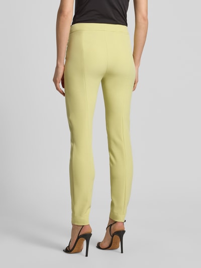 Vrouwenmodel draagt Slim Fit Schmale broek met LOGO-studs model 'HAGONIA-1' van HUGO, look: effen, materiaalverwerking: stretch, persplooien, steekzakken, mid taille, slim fit, met riemlussen, sluiting: haakje en verborgen ritssluiting, kleur lichtgeel, zijaanzicht, volledig lichaam rugaanzicht.