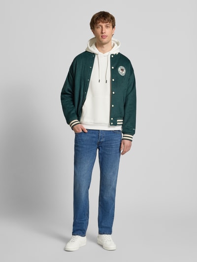 Männermodel trägt Hoodie mit Kapuze Modell 'BRADLEY' von Jack & Jones in Weiß, lockerer Schnitt, Känguru-Tasche, Ganzkörperansicht von vorne.