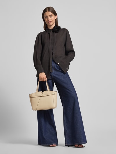 Frauenmodel trägt Henkeltasche aus Rindsleder Modell 'REVERS' von BOSS, beige, rechteckig, glatte Struktur, Ganzkörperansicht von vorne.