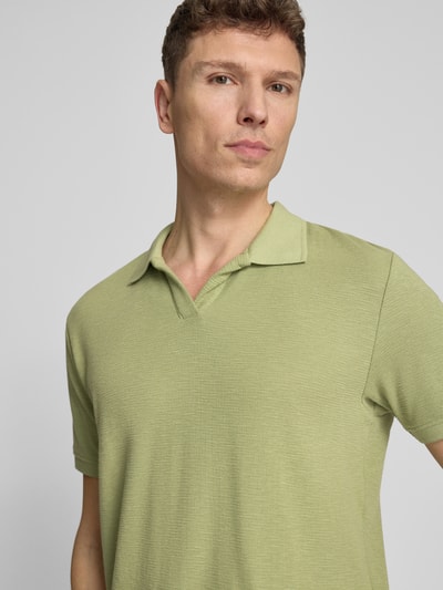 Männermodel trägt Comfort Fit Poloshirt mit V-Ausschnitt von Lindbergh, Reine Baumwolle, Strukturmuster, Label-Detail, Nahaufnahme Oberkörper.