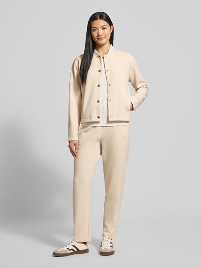 Frauenmodel trägt Sweatjacke mit Stehkragen Modell 'Tobina' von JOOP! im Regular-Fit aus Material-Mix mit Modal-Anteil in Beige, Knopfleiste und Eingrifftaschen, Ganzkörperansicht von vorne.