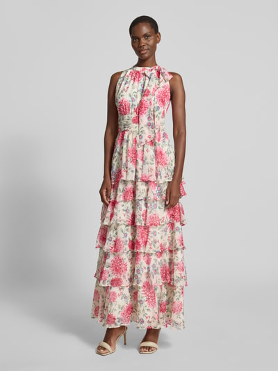 Frauenmodel trägt Maxikleid mit Schluppe Modell 'Marli' von Neo Noir aus Chiffon mit floralem Print, Taillierter Schnitt, Volantsaum, Rückseitiger Schlüsselloch-Ausschnitt, rückseitige Smok-Details, Ganzkörperansicht von vorne.