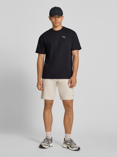 Männermodel trägt schwarzes Relaxed Fit T-Shirt aus reiner Baumwolle Modell 'ESS ELEVATED' von PUMA, Herren T-Shirt von PUMA Performance, Ganzkörperansicht von vorne.