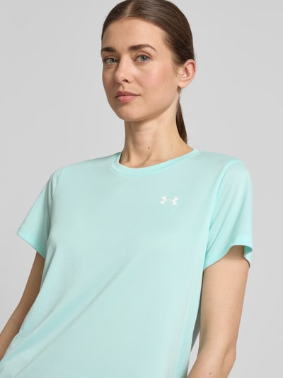 Vrouwenmodel draagt Funktionsshirt mit Rundhalsausschnitt und Logo van Under Armour in regular fit, lichtblauw, logo links, damesshirt, ruglengte maat S 61 cm, close-up bovenlichaam.