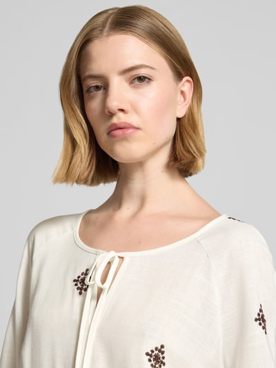 Frauenmodel trägt Bluse aus Viskose-Mix mit 3/4-Arm von Christian Berg Woman Selection in Creme mit Stickerei, Nahaufnahme Oberkörper. Leichte Struktur, Schlüsselloch-Ausschnitt mit Schnürung, Straight Fit, elastischer Abschluss am Ärmel, Viskose-Mix mit Leinen-Anteil.