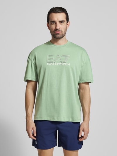 Männermodel trägt T-Shirt mit Logo und Rundhalsausschnitt von EA7 Emporio Armani in Hellgrün, Reine Baumwolle, Regular-Fit, Logo, Rückenlänge 68 cm bei Größe M, Ganzkörperansicht von vorne.