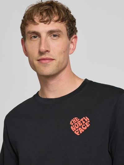 Männermodel trägt T-Shirt mit Label-Print und Rundhalsausschnitt von The North Face in Schwarz, Reine Baumwolle, Regular-Fit, Nahaufnahme Oberkörper.