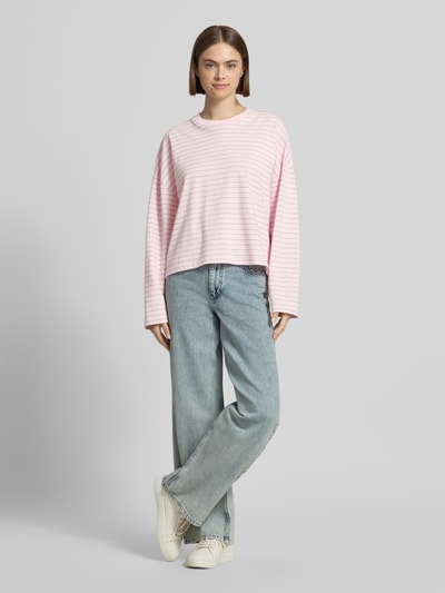Frauenmodel trägt Longsleeve mit rückseitigem Statement-Print von OH APRIL in Rosa mit feinen Streifen, Reine Baumwolle, Loose-Fit, Rundhalsausschnitt, Rückenlänge bei Größe S: 53 cm, Ganzkörperansicht von vorne.