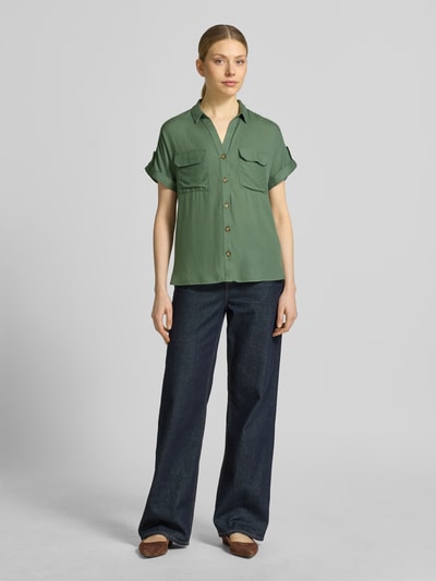 Modelka kobieca ma na sobie Regular Fit Hemdbluse aus reiner Viskose Modell 'BUMPY' od Vero Moda, zielony, dwa kieszenie, krótki rękaw, krój regular fit, czysty len, przód zapięcie na guziki, widok całej sylwetki z przodu.