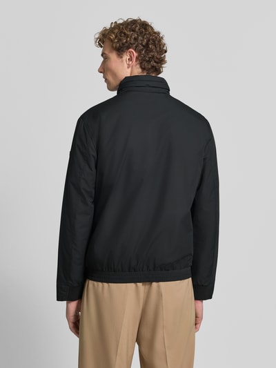 Męski model nosi czarną kurtkę pikowaną Regular Fit Steppjacke mit Stehkragen Modell 'LIGHT' von Strellson, Ganzkörperansicht Rückansicht, kurtka pikowana męska marki Strellson
