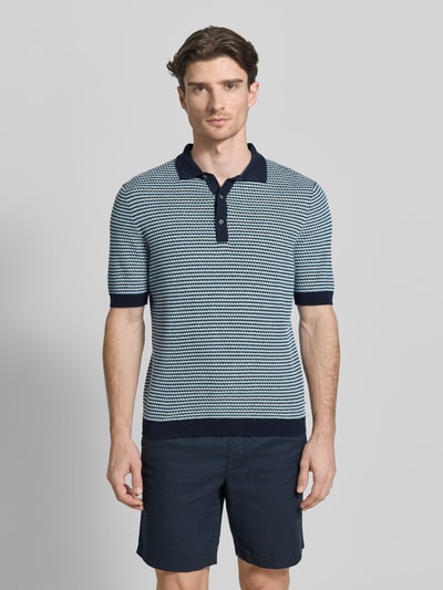 Männermodel trägt Slim Fit Poloshirt in Strick-Optik mit Leinen-Anteil von Brax, blauer Baumwoll-Mix, elastische Abschlüsse, Ganzkörperansicht von vorne.