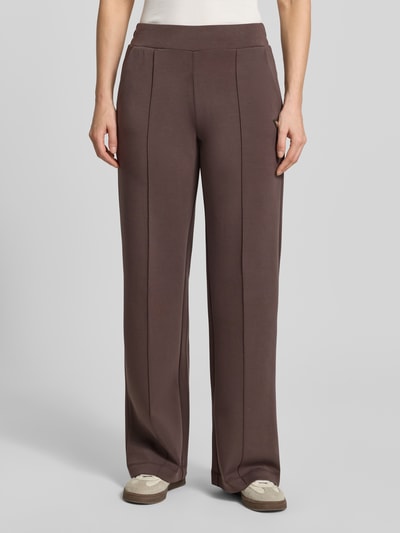 Frauenmodel trägt Straight Fit Stoffhose mit Modal-Anteil Modell 'Olympe' von Guess Activewear in Braun, Elastischer-Material-Mix, Ganzkörperansicht von vorne. Damen Stoffhose mit Elastikbund, Innenbeinlänge bei Größe S: 80 cm.