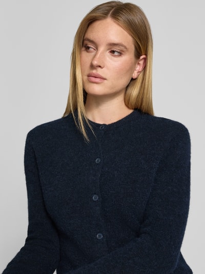 Kobiece modelka nosi kardigan Regular Fit Cardigan aus Woll-Alpaka-Mix Model 'NOR' od Samsøe Samsøe w imitacji dzianiny, długi rękaw, okrągły dekolt, gładka granatowa tkanina z listwą guzikową, mieszanka wełny i alpaki, długość tyłu 59 cm, długość rękawa 62 cm, ujęcie: zbliżenie na górną część ciała.