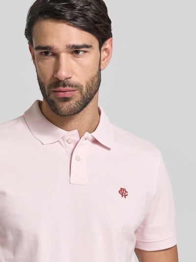 Männermodel trägt Slim Fit Poloshirt mit Logo-Stitching von MCNEAL in Rosa, reine Baumwolle, Polokragen, Nahaufnahme Oberkörper.