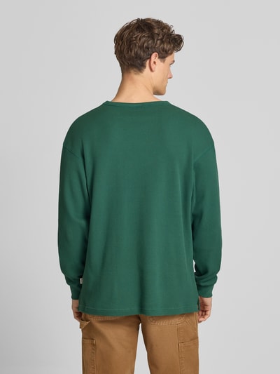 Mannenmodel draagt heren shirt met lange mouwen van puur katoen met structuurpatroon, ronde hals, gestikt logo, ruglengte maat S 75 cm, Longsleeve met Logo-Stitching van BLKVIS, geheel groene kleur, loose fit, Ganzkörperansicht Rückansicht.