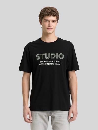 Männermodel trägt Relaxed Fit T-Shirt aus reiner Baumwolle von Tom Tailor Denim, Optik: Unifarben, Label-Print, Rundhals, Kurzarm, Ganzkörperansicht von vorne.