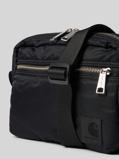 Produktfoto, Tasche mit Logo-Print von Carhartt Work In Progress in Schwarz, glatte Textur, silberne Reißverschlüsse, wasserabweisend, Nahaufnahme