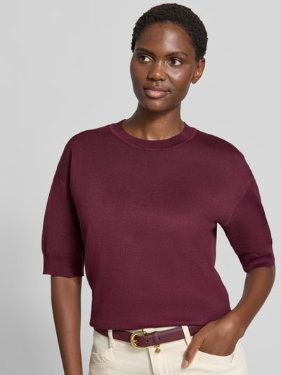 Modelka kobieca ma na sobie damski t-shirt Relaxed Fit T-Shirt aus Viskose-Mix od b.young w kolorze bordowym, mieszanka wiskozy, prążkowana plisa, okrągły dekolt, rękaw o dł. 1/2, prążkowane zakończenia rękawów, długość tyłu w rozmiarze S: 56 cm, długość rękawów w rozmiarze S: 24 cm, widok na górną część ciała, z przodu.