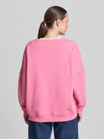 Frauenmodel trägt Oversized Sweatshirt aus reiner Baumwolle von miss goodlife in Rosa mit Pailettenbesatz, elastische Abschlüsse, Ganzkörperansicht Rückansicht.