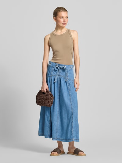 Frauenmodel trägt Jeansrock mit Schnürung Modell 'LONIA' von Bash in heller Denimfarbe, A-Linie, reine Baumwolle, Ganzkörperansicht von vorne.