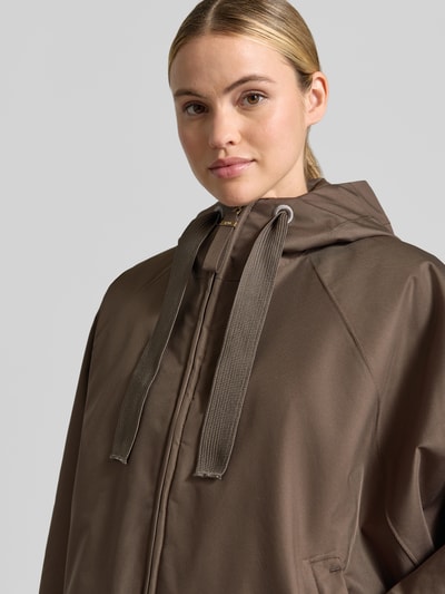 Frauenmodel trägt Relaxed Fit Mantel mit Kapuze Modell 'PURE' von g-lab in Braun mit Tunnelzug und Eingrifftaschen, Nahaufnahme Oberkörper.