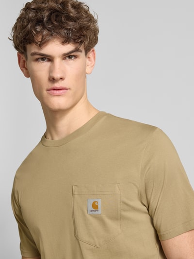 Männermodel trägt Regular Fit T-Shirt mit Logo-Patch von Carhartt Work In Progress in Beige, reine Baumwolle, Brusttasche, Nahaufnahme Oberkörper