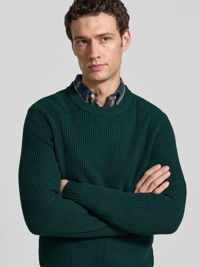 Männermodel trägt Regular Fit Strickpullover aus reiner Baumwolle von MCNEAL, dunkelgrün, Rundhalsausschnitt, Nahaufnahme Oberkörper.