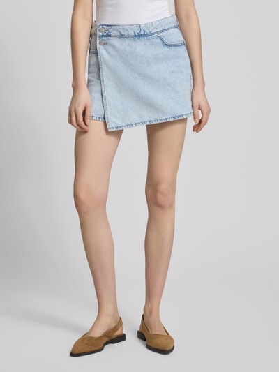 Frauenmodel trägt Skort mit Knopfverschluss Modell 'GRETA' von JJXX aus Reine Baumwolle, Denim-Optik, Gerader-Schnitt, Minirock, Ganzkörperansicht von vorne.